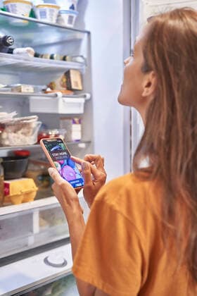 IMAGO Creative: Haushaltsgeräte - Kühlschrank Woman checking refrigerator while ordering groceries through mobile application model released Symbolfoto property released ABIF01499