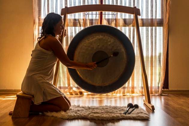 Sound healerl playing gong while sitting by window model released Symbolfoto property released DLTSF02125