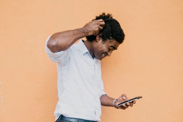 IMAGO Creative: Digitale Welt, Social Commerce Frustrated man using smart phone in front of beige wall model released Symbolfoto DSIF00557