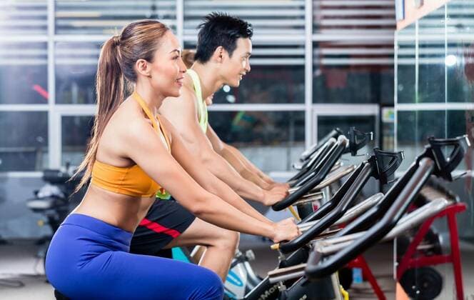  Sportive Asian couple doing indoor cycling in gym model released, Symbolfoto, 12.10.2020, Copyright: xKzenonx Panthermedia25859690