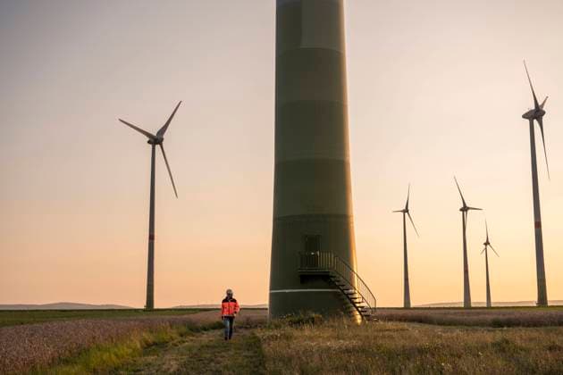 Male engineer walking on meadow in front of wind turbines model released Symbolfoto UUF24604