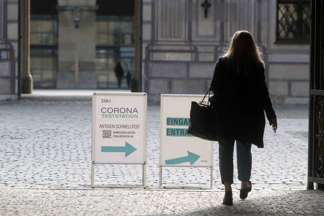 Stand with label Corona Teststation Antigen Rapid Test 21DX with directional arrow is located in downtown Munich, Bavaria, Germany