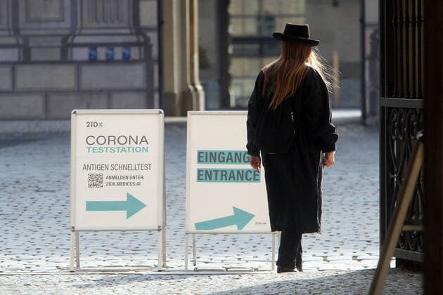 Stand with label Corona Teststation Antigen Rapid Test 21DX with directional arrow is located in downtown Munich, Bavaria, Germany