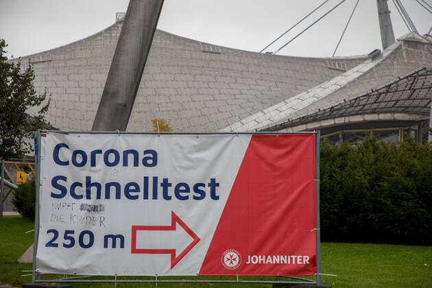 Muenchen, Germany 08 October 2021 In front of the Olympic stadium in Munich stands an advertising banner, signposts for a Corna quick test of the Johanniter On the banner was handwritten an addition, vaccinates the children, written Bavaria Copyright: xFotostandx xFritschx