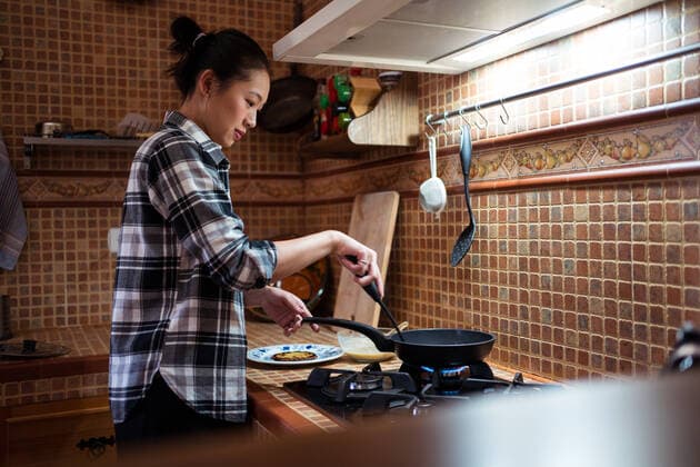 IMAGO Creative: Kulturelle Folgen der Pandemie: Gesundheitsbewu?tsein und Alleinsein Side view of focused young Asian female in casual clothes cooking yummy pancakes using spatula while standing in kitchen JuanAlbertoRuiz_PancakesVideo_3.jpg Copyright: xJuanxAlbertoxRuizx Model Released