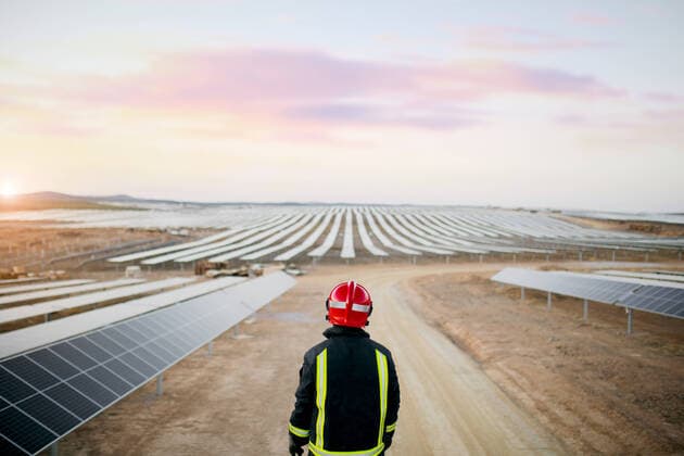 IMAGO Creative: 2021 Favoriten IMAGO Creative: Corporate: Klimaschutz, Digitalisierung und Urbanisierung Back view of anonymous person wearing red helmet and protective clothes while standing in field with solar energy panels on sunny day, Model released SergioVictorVega_Firefighter_15.jpg Copyright: xSergioxVictorxVegax MR