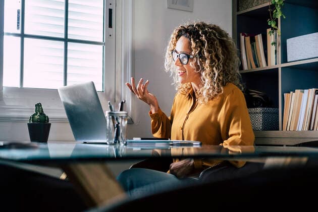 Smiling businesswoman gesturing during video conference through laptop at home model released Symbolfoto property released SIPF02473