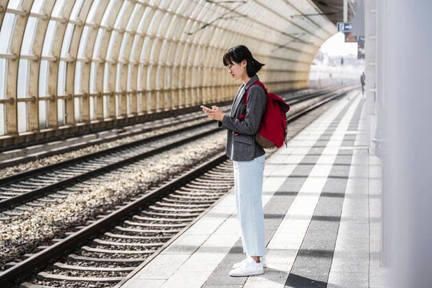 IMAGO Creative: Neue Aussichten Teenage girl with backpack using mobile phone at train station model released Symbolfoto UUF24849