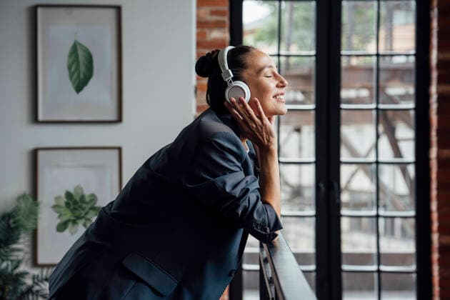 Mid adult businesswoman listening music through headphones in office model released Symbolfoto property released VPIF05014