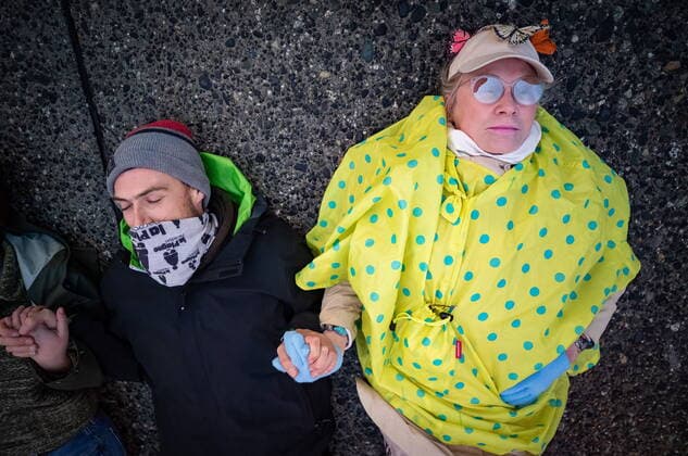 October 25, 2021, Richmond, BC, Canada: A man holds the hand of an elderly woman while lying on the street during a protest organized by the environmental activist group Extinction Rebellion where they blocked the main road used to access Vancouver International Airport, in Richmond, B.C., Monday, Oct. 25, 2021. More than a dozen people were arrested and traffic to and from the airport was diverted due to the protest which was part of the group s two week October Rebellion action. Richmond Canada  - ZUMAc35_ 20211025_zaf_c35_125 Copyright: xDarrylxDyckx