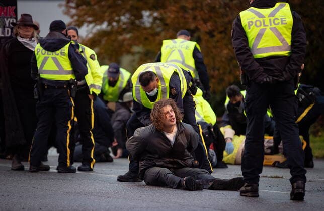 October 25, 2021, Richmond, BC, Canada: RCMP officers process protesters that were taken into custody after the environmental activist group Extinction Rebellion blocked the main road used to access Vancouver International Airport, in Richmond, B.C., Monday, Oct. 25, 2021. More than a dozen people were arrested and traffic to and from the airport was diverted due to the protest which was part of the group s two week October Rebellion action. Richmond Canada  - ZUMAc35_ 20211025_zaf_c35_127 Copyright: xDarrylxDyckx