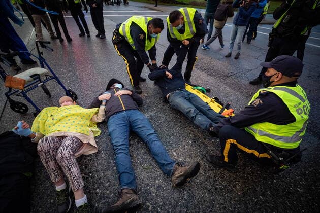October 25, 2021, Richmond, BC, Canada: RCMP officers use a spinal board to take a person into custody after the environmental activist group Extinction Rebellion blocked the main road used to access Vancouver International Airport, in Richmond, B.C., Monday, Oct. 25, 2021. More than a dozen people were arrested and traffic to and from the airport was diverted due to the protest which was part of the group s two week October Rebellion action. Richmond Canada  - ZUMAc35_ 20211025_zaf_c35_128 Copyright: xDarrylxDyckx
