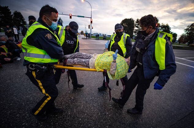October 25, 2021, Richmond, BC, Canada: An elderly woman gestures as RCMP officers use a stretcher to take her into custody after the environmental activist group Extinction Rebellion blocked the main road used to access Vancouver International Airport, in Richmond, B.C., Monday, Oct. 25, 2021. More than a dozen people were arrested and traffic to and from the airport was diverted due to the protest which was part of the group s two week October Rebellion action. Richmond Canada  - ZUMAc35_ 20211025_zaf_c35_137 Copyright: xDarrylxDyckx