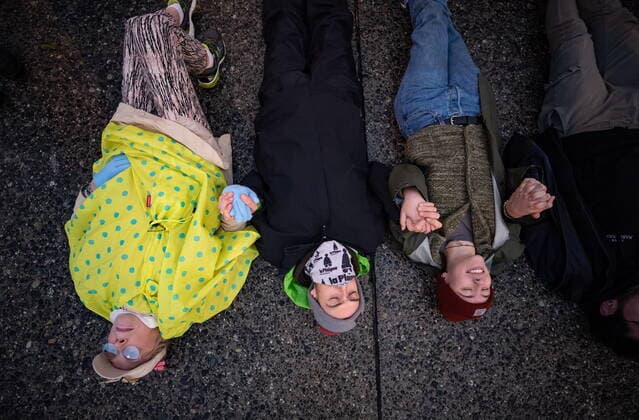 October 25, 2021, Richmond, BC, Canada: People hold hands while lying on the street during a protest organized by the environmental activist group Extinction Rebellion where they blocked the main road used to access Vancouver International Airport, in Richmond, B.C., Monday, Oct. 25, 2021. More than a dozen people were arrested and traffic to and from the airport was diverted due to the protest which was part of the group s two week October Rebellion action. Richmond Canada  - ZUMAc35_ 20211025_zaf_c35_140 Copyright: xDarrylxDyckx