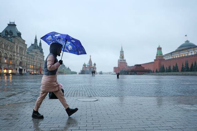 MOSCOW, RUSSIA - OCTOBER 28, 2021: A woman with an umbrella crosses the deserted Red Square. A recent surge in COVID-19 cases in Russia has prompted the Moscow authorities to declare non-working days with pay from October 28 to November 7. Sergei Bobylev TASS  TS116099