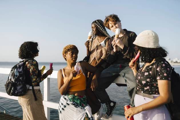IMAGO Creative: Frauenmonat im März IMAGO Creative: Digitale Welt, Verzicht auf Technologie LGBTQIA multiracial friends eating ice creams on railing during sunny day Sweden, Malmo, model released Copyright: xMaskotx , MA89709