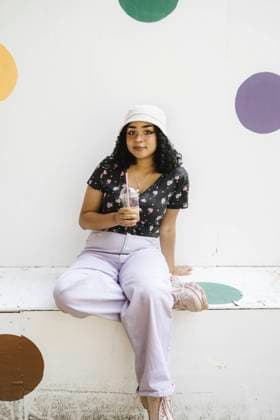 Portrait of teenage girl holding drink while sitting on retaining wall Sweden, Malmo, model released Copyright: xMaskotx , MA89760