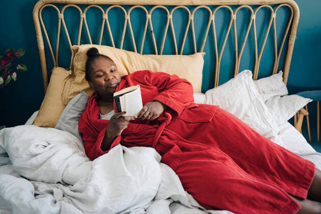 IMAGO Creative: Kulturelle Folgen der Pandemie: Gesundheitsbewußtsein und Alleinsein Creative Highlights Symbolbilder Mid adult woman reading book while relaxing on bed Sweden, Stockholm, model released, property released Copyright: xMaskotx , MA90068
