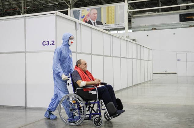Coronavirus in Russland, EindrÃ¼cke aus provisorischer Covid-19-Einrichtung in Moskau MOSCOW REGION, RUSSIA - NOVEMBER 12, 2021: A medical worker moves a patient in the red zone of a temporary COVID-19 facility at the Patriot Convention and Exhibition Center of the Russian Armed Forces in the town of Kubinka near Moscow. Moscow Region is listed third after Moscow and St Petersburg with the highest number of COVID-19 cases in Russia; over 1,000 people are hospitalized in the region daily. Gavriil Grigorov TASS  TS117A6E