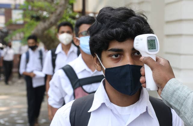 Schools Reopen After Two Years In Kolkata A staff checks the body temperature of a student at the entrance of School and maintain social distancing and covid protocol at the first day a classroom at a School in Kolkata, India on November 16,2021 Kolkata India  Copyright: xDebajyotixChakrabortyx chakraborty-notitle211116_npPz3