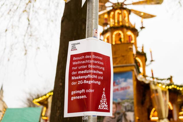 Sign of the city of Bonn with the inscription Besuch des Weihnachtsmarktes nur unter Beachtung der medizinischen Maskenpflicht und der 2G Regelung geimpft oder genesen Opening day of the Christmas market 2021 on the Münsterplatz in Bonn 17 10 2021 Bonn Innenstadt NRW Germany
