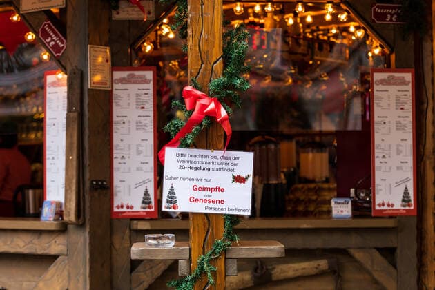 A sign with the inscription Please note that the Christmas market takes place under the 2G rule Therefore, we may only serve vaccinated or recovered persons The Bonn Christmas market in the shadow of the Corona pandemic On the market site, the 2G rule applies vaccinated or recovered In addition, the mask requirement in the inner city area