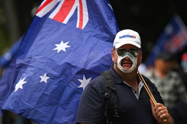 COVID19 FREEDOM RALLY SYDNEY, A man wearing a mask with a hole cut out of it holds an Australian flag during The Worldwide Rally for Freedom protest against mandatory vaccinations and lockdown measures in Sydney, Saturday, November 20, 2021. The Worldwide Rally for Freedom is a day of rallies purportedly for freedom across many countries, including Australia. ( NO ARCHIVING, EDITORIAL USE ONLY, NO USE IN BOOKS WITHOUT CONSENT SYDNEY NSW AUSTRALIA  Copyright: xStevenxSaphorex 20211120001598370873