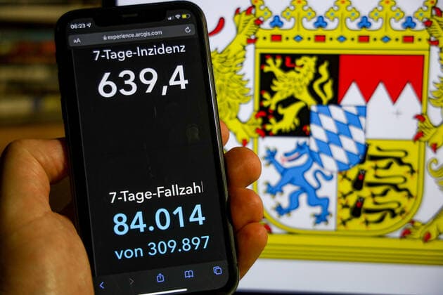 Coronavirus in Deutschland - Covid-19-Dashboard des Robert Koch-Institut DEU, Deutschland, Bayern 21.11.2021: Die 7-Tage-Inzidenz für das Bundesland (Fälle letzte 7 Tage 100.000 EW) wird auf einem iPhone angezeigt, im Hintergrund das Landeswappen