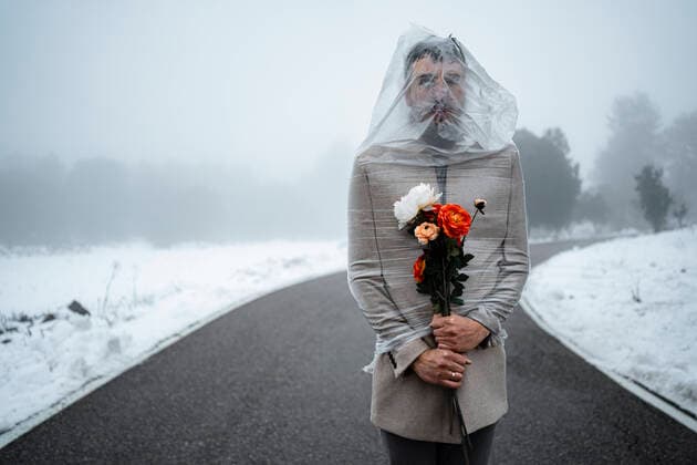 Mature man wrapped in plastic holding bunch of flowers on road model released, RCPF01376
