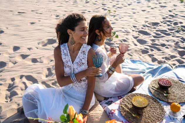 Female friends holding drinking glasses on beach model released, RFTF00113