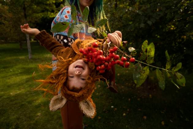 Mother carrying cheerful daughter holding fruit branch at park model released, SSGF00047