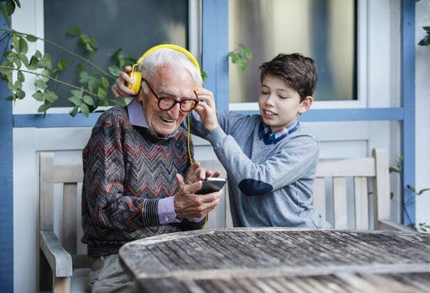 Boy adjusting grandfather s headphones on bench model released property released, Stockdorf Bayern Deutschland Ina-Seidel-Strasse AANF00187