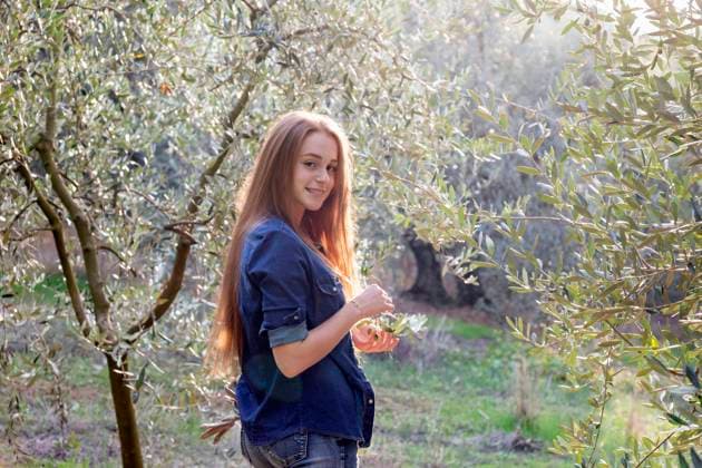 Smiling young woman with long hair amidst olive trees at countryside model released, EIF02336