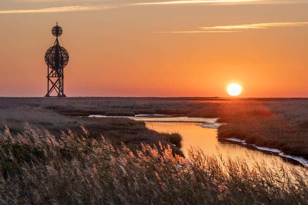 Germany, Hamburg, Coastal landscape of Hamburg Wadden Sea National Park at sunset with Ostbake Neuwerk beacon in background, KEBF02071