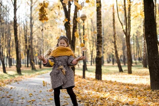 Carefree girl throwing autumn leaves on walkway in park model released, LLUF00337