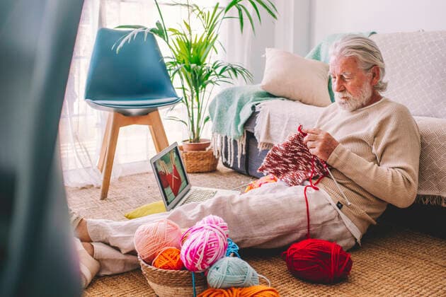 Senior man learning to knit wool through laptop at home model released property released, SIPF02694
