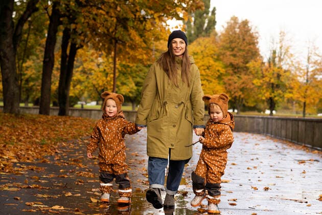 Smiling mother holding hands of twins at autumn park model released, SSGF00159