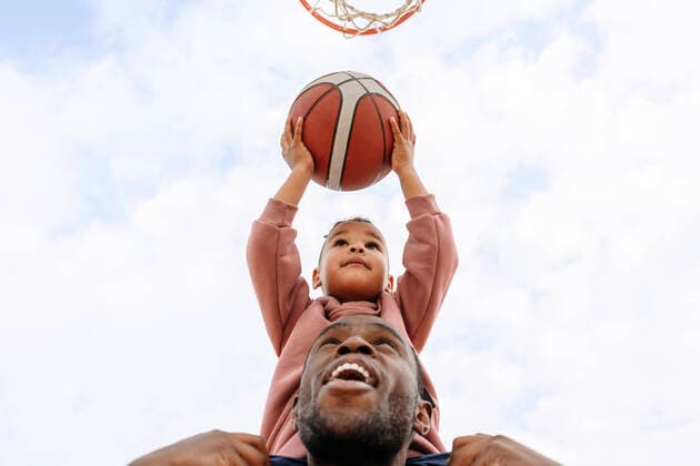 IMAGO Creative: Lokalhelden - Jugendsportbildung Father helping son putting basketball in hoop model released, VYF00704