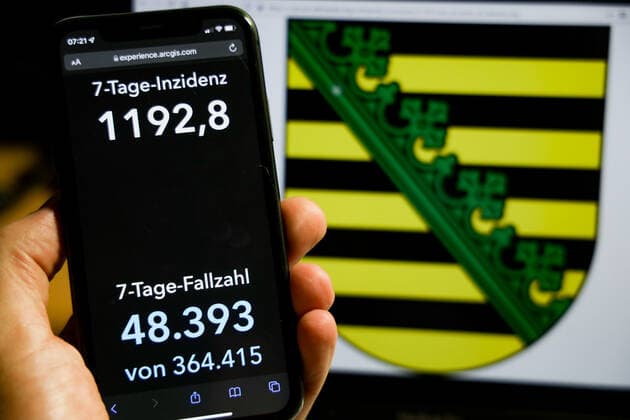 Coronavirus in Germany Covid 19 Dashboard of the Robert Koch Institute DEU, Germany, Saxony 26 11 2021 The 7-day incidence for the state Cases last 7 days 100 000 PE is displayed on an iPhone, with the state coat of arms in the background.