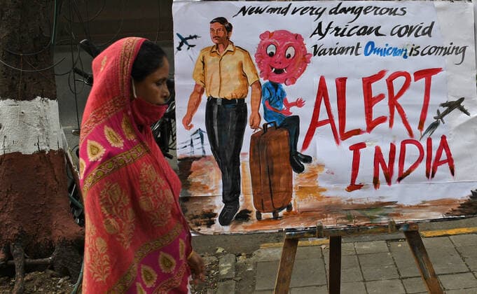 November 27, 2021, Mumbai, Maharashtra, India: A woman wearing a protective face mask lowered to her chin walks past a painting made by Gurukul school of art to create awareness about the new variant of coronavirus which has emerged in South Africa..Brihanmumbai Municipal Corporation (BMC) as a precautionary measure will quarantine South Africa returnees on arrival in Mumbai. Mumbai India - ZUMAs197 20211127_zaa_s197_058 Copyright: xAshishxVaishnavx