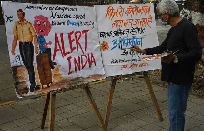 November 27, 2021, Mumbai, Maharashtra, India: A man wearing a protective face mask paints a poster to create awareness about new variant of coronavirus which has emerged in South Africa..Brihanmumbai Municipal Corporation (BMC) as a precautionary measure will quarantine South Africa returnees on arrival in Mumbai. Mumbai India - ZUMAs197 20211127_zaa_s197_050 Copyright: xAshishxVaishnavx