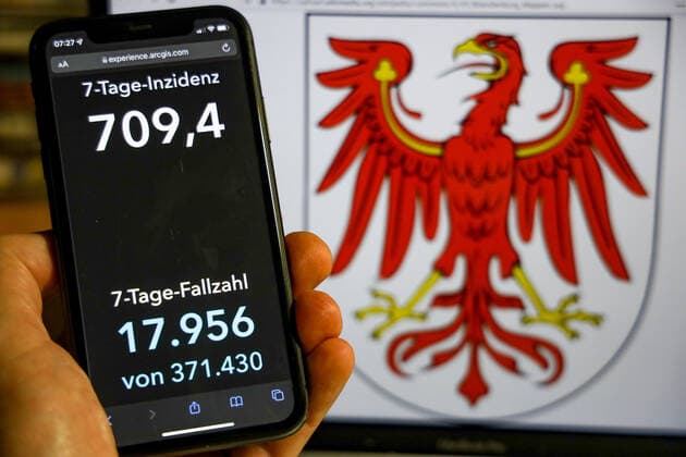 Coronavirus in Germany Covid 19 Dashboard of the Robert Koch Institute DEU, Germany, Brandenburg 28 11 2021 The 7-day incidence for the state Cases last 7 days 100 000 p.e. is displayed on an iPhone, with the states coat of arms in the background