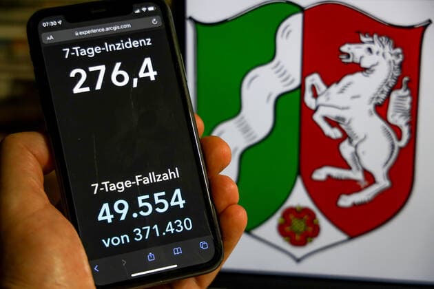 Coronavirus in Germany Covid 19 Dashboard of the Robert Koch Institute DEU, Germany, North Rhine Westphalia 28 11 2021 The 7-day incidence for the state Cases last 7 days 100 000 PE is displayed on an iPhone, with the states coat of arms in the background