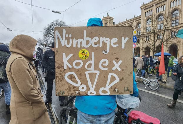 November 28, 2021, Munich, Bavaria, Germany: A sign with the words Nuremberg Code and Markus Soeder on it. The Nuremburg Codes is a beloved element of conspiracy theorists and QAnons where they believe physicians, researchers, and nurses should stand before tribunals and eventually executed for taking part in the Corona crisis and vaccinations. Despite southern Bavaria being in the clutches of a brutal fourth wave and beingnonnthe cusp of a Delta and Omicron Winter, Corona deniers from throughout Germany banded together without respecting any of the infection control regulations to memorialize disgraced former police officer and conspiracy theorist Karl Hilz who died after being reported by those in his circles as a pneumonia . Sin - ZUMAb160 20211128_zbp_b160_009 Copyright: xSachellexBabbarx