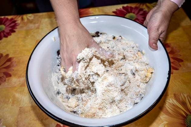 mischen und kneten der Zutaten für Stollenteig mit den Händen in einer weißen Schüssel *** mix and knead the ingredients for stollen dough with your hands in a white bowl 1049002938