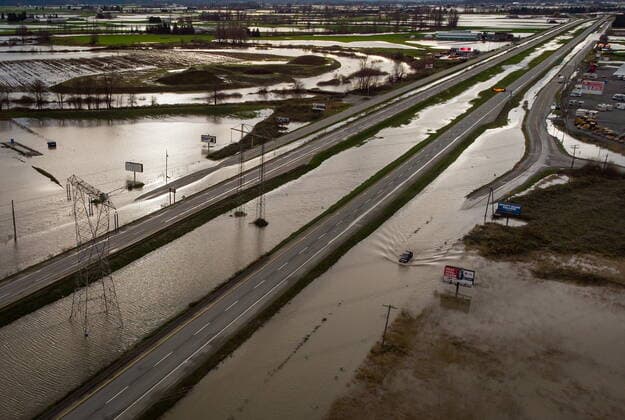 December 1, 2021, Abbotsford, British Columbia, Canada: A motorist drives on a water logged service road along the closed Trans-Canada Highway as floodwaters fill the ditches beside the highway and farmland in Abbotsford. Abbotsford Canada  - ZUMAc35_ 20211201_zaf_c35_097 Copyright: xDarrylxDyckx