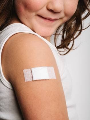 Side view of cropped unrecognizable schoolgirl after vaccination standing with band aid on arm, Model released HodeiUnzueta_VaccinatedKids_25.jpg Copyright: xHodeixUnzuetax MR