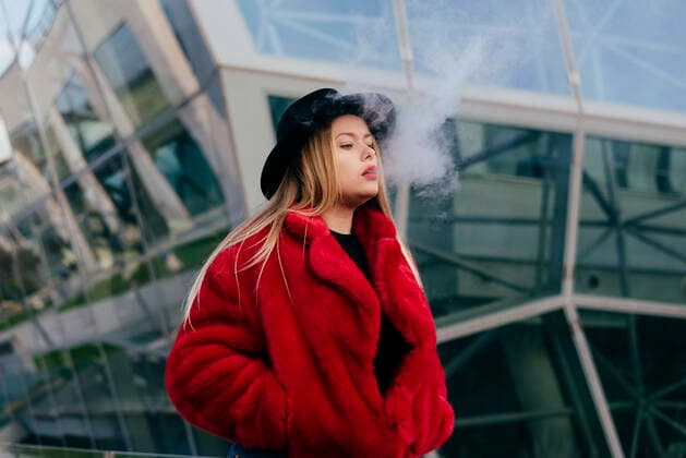 Creative Highlights Symbolbilder Cute blonde young woman with hat and red jacket smoking with vaper machine on the street, Model released ManuelRuizAlba_BlondieYoungWoman_24.jpg Copyright: xManuelxRuizxAlbax MR
