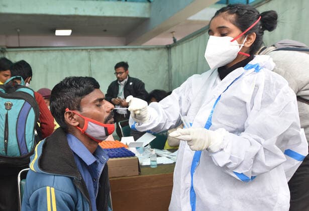 NEW DELHI, INDIA - DECEMBER 2: A health worker collects a swab sample of a passenger for Covid-19 test during a special testing camp organised after Omicron Covid Variant identified at Anand Vihar Railway Station, on December 2, 2021 in New Delhi, India. (Photo by Sonu Mehta Hindustan Times) Daily Life Amid Coronavirus Pandemic In India