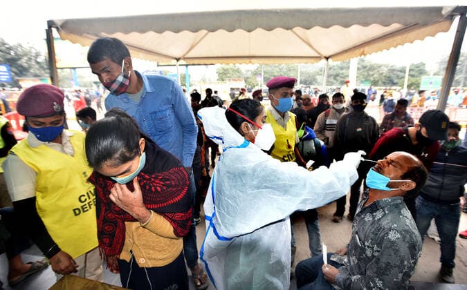 NEW DELHI, INDIA - DECEMBER 2: A health worker collects a swab sample of a passenger for Covid-19 test during a special testing camp organised after Omicron Covid Variant identified at Anand Vihar Railway Station, on December 2, 2021 in New Delhi, India. (Photo by Sonu Mehta Hindustan Times) Daily Life Amid Coronavirus Pandemic In India